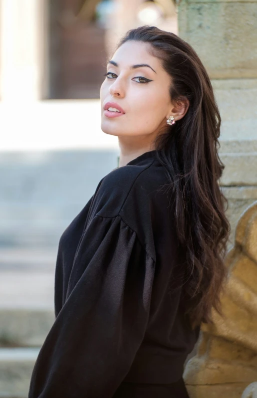 a beautiful woman leaning against a building wall