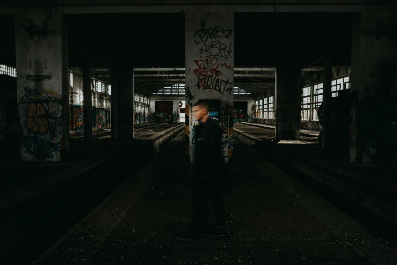 a man standing alone on train tracks in the dark