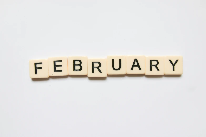 small scrabble letters arranged on top of each other spelling the words february