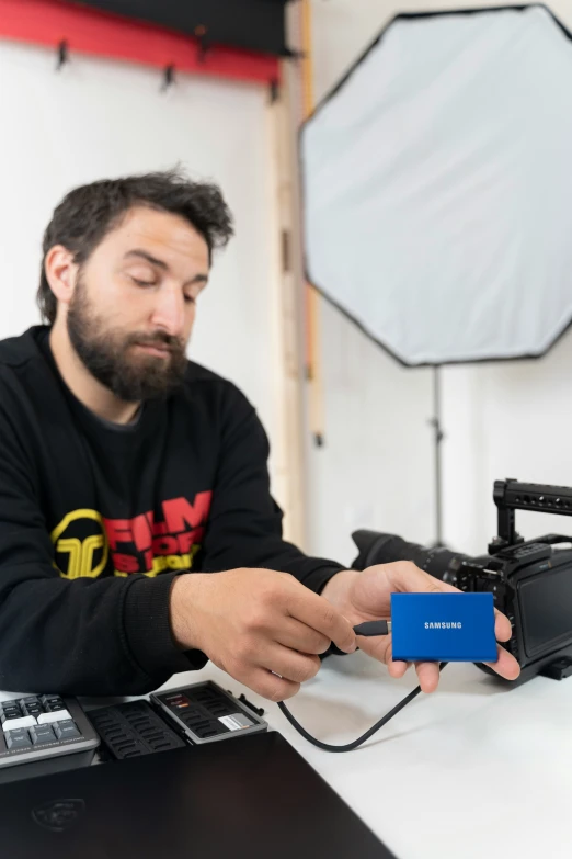 a man is working on a camera near a laptop