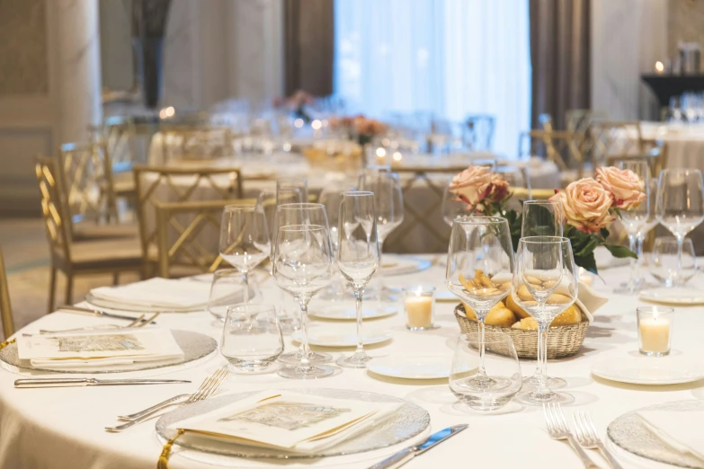 a table has white cloths, silverware and flower centerpieces on it