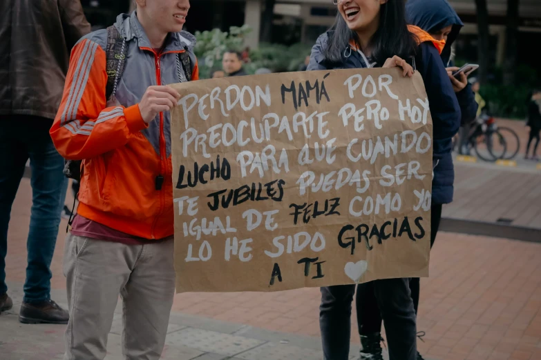 a man holds a brown sign with black writing