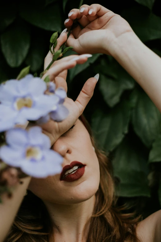 young woman in dark lipstick holding flowers