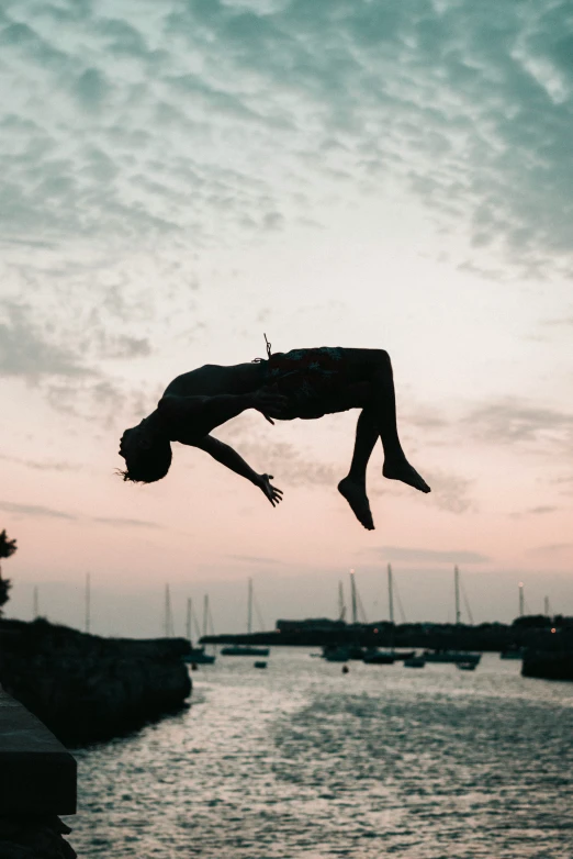 man in mid air, jumping in to the water from pier