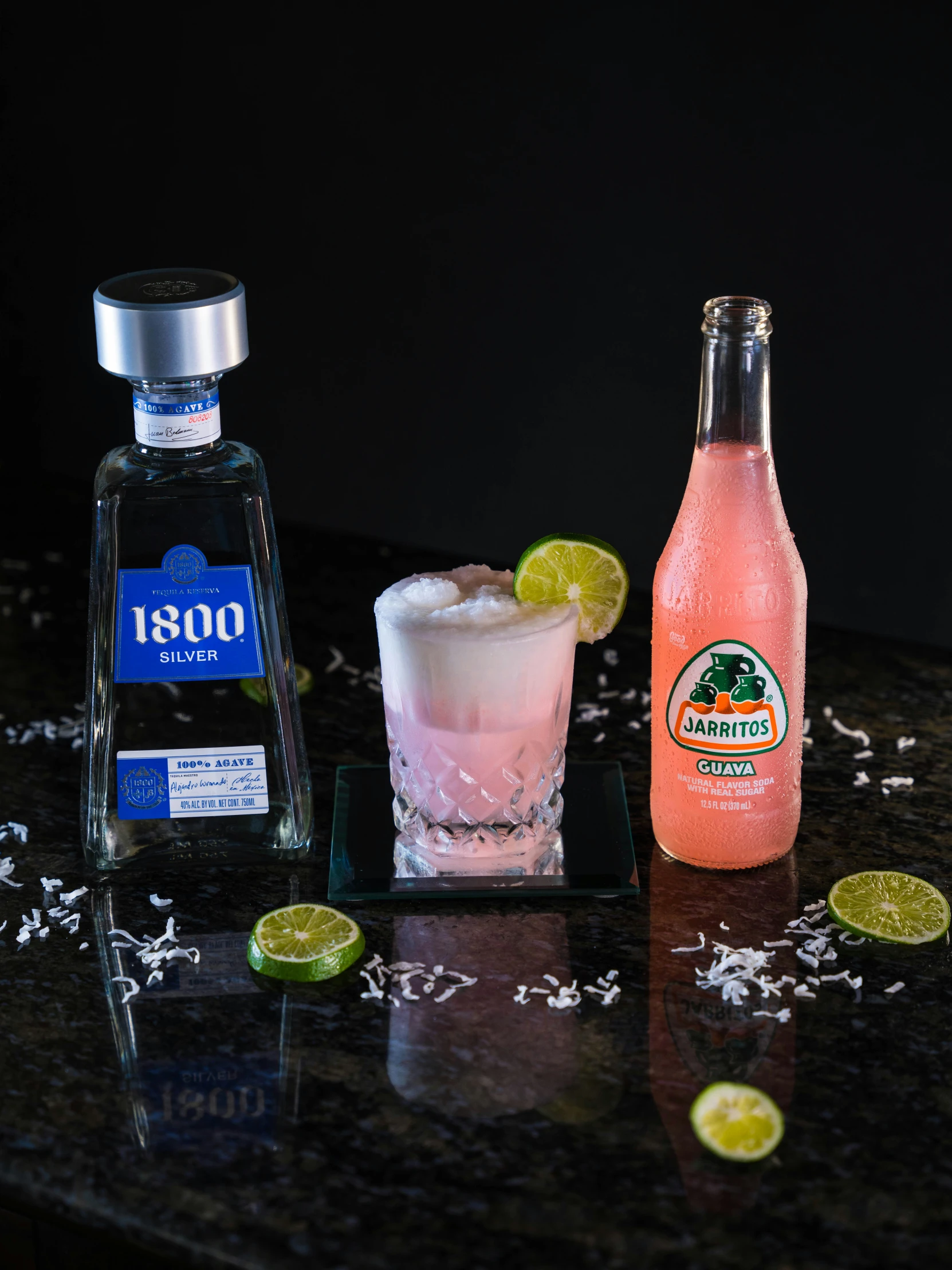 bottle of gin, liquor glass and lime on counter top