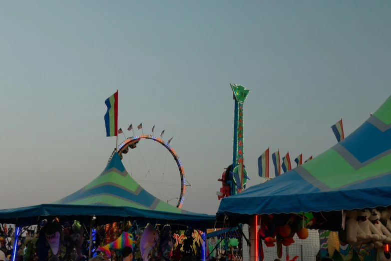 some tents are next to ferris wheel and ride