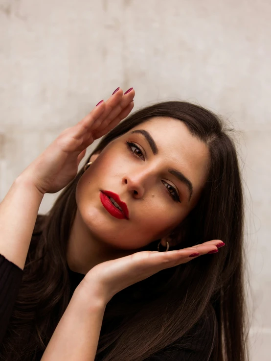 a young woman poses with her hand on the side of her face