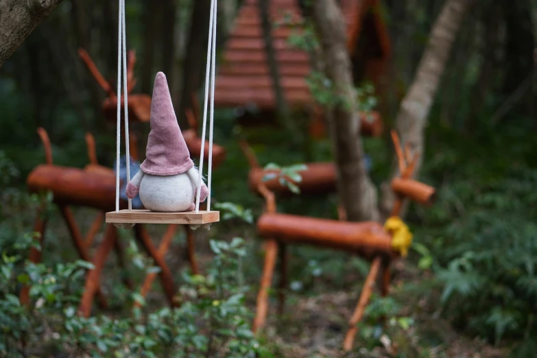 a stuffed animal toy on a swing hanging from a tree