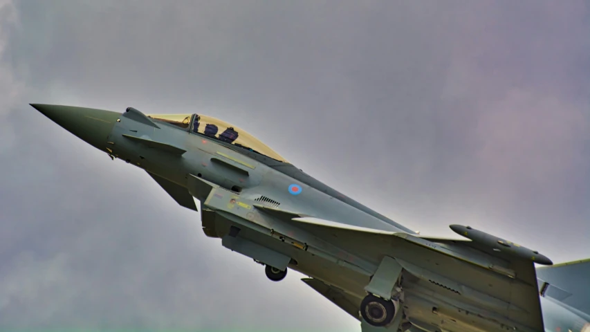 a fighter jet flying through the air in a cloudy sky