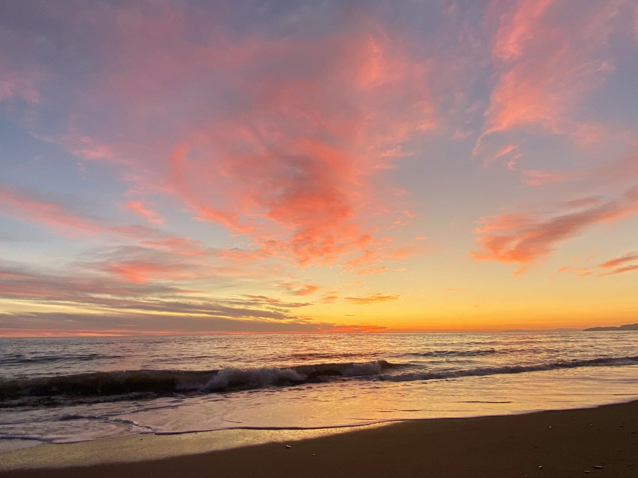 there are waves crashing into the shore with the sun going down