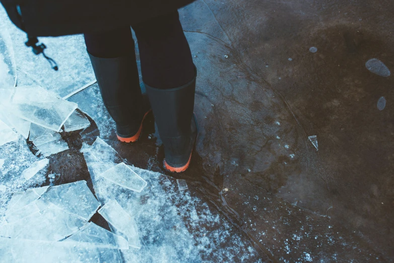 person wearing orange boots in the snow on a sidewalk