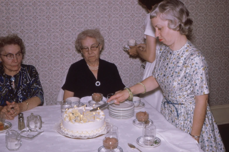 the women are sitting at the table and  the cake