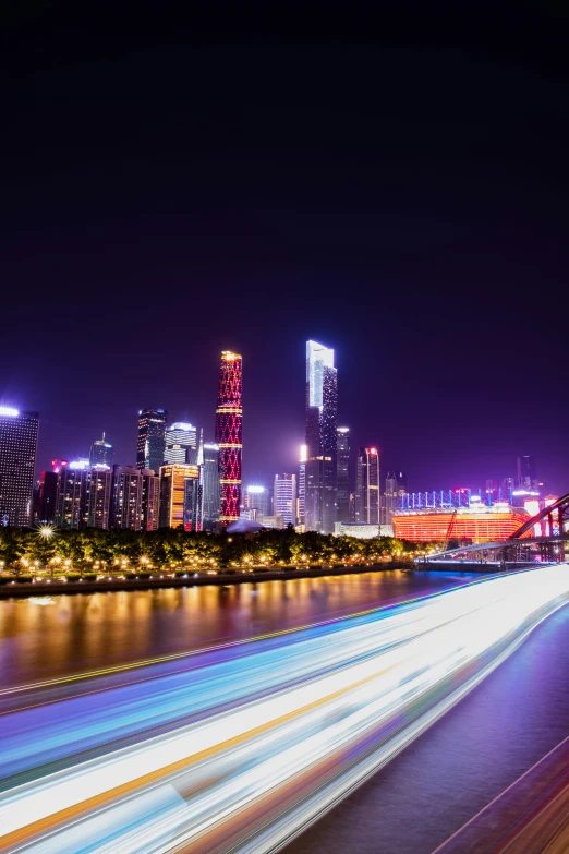 a night view shows a city skyline with skyscrs and light trails