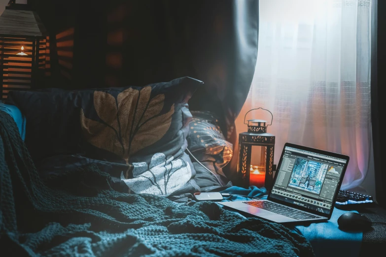 a laptop computer and a candle on the bed