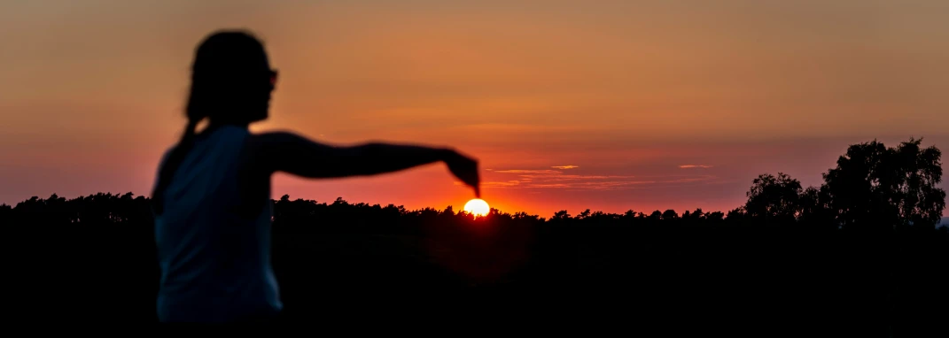 a lady watching the sun go down with the shadow of her arms stretched out