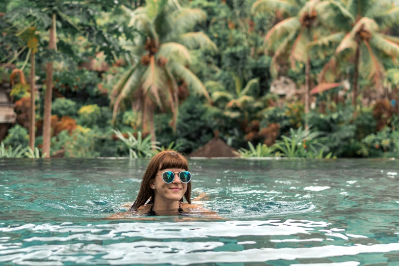 a woman wearing shades floating in a pool of water