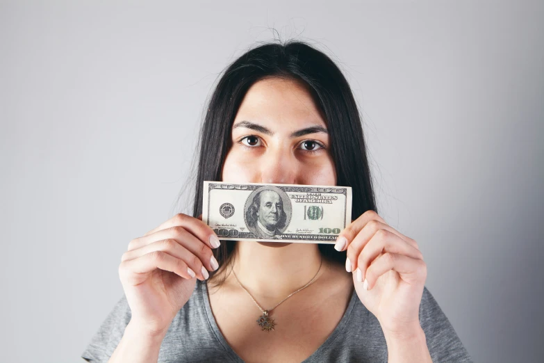 a woman is holding out a dollar bill to her face