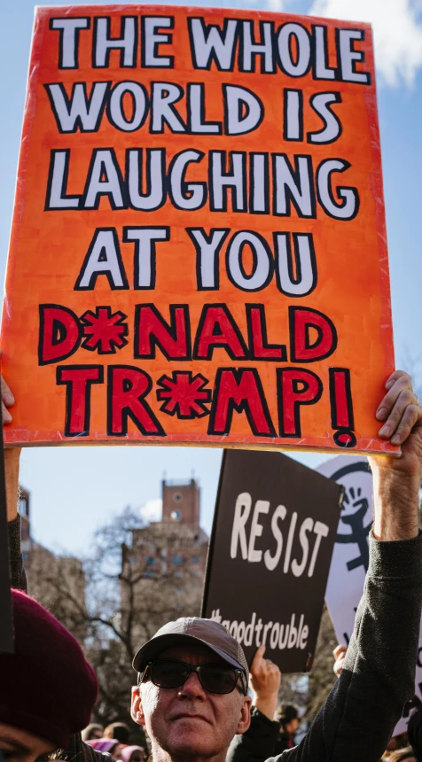 man holding orange protest sign during rally for climate protection