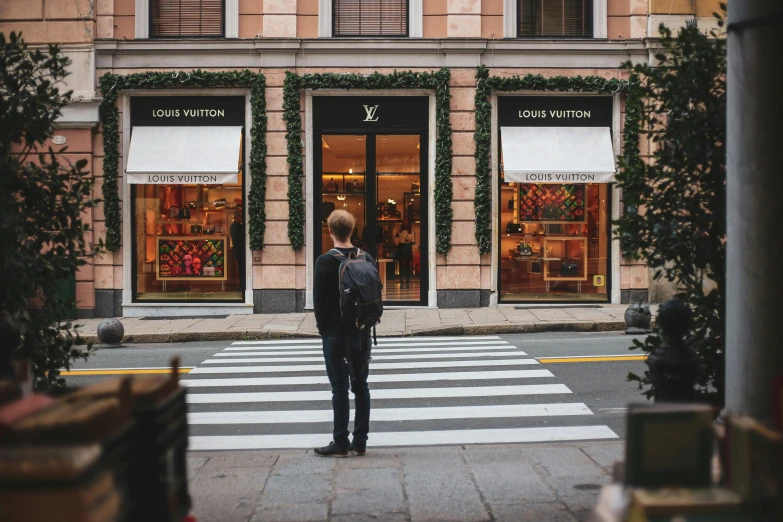 a person standing at a crosswalk in front of a building