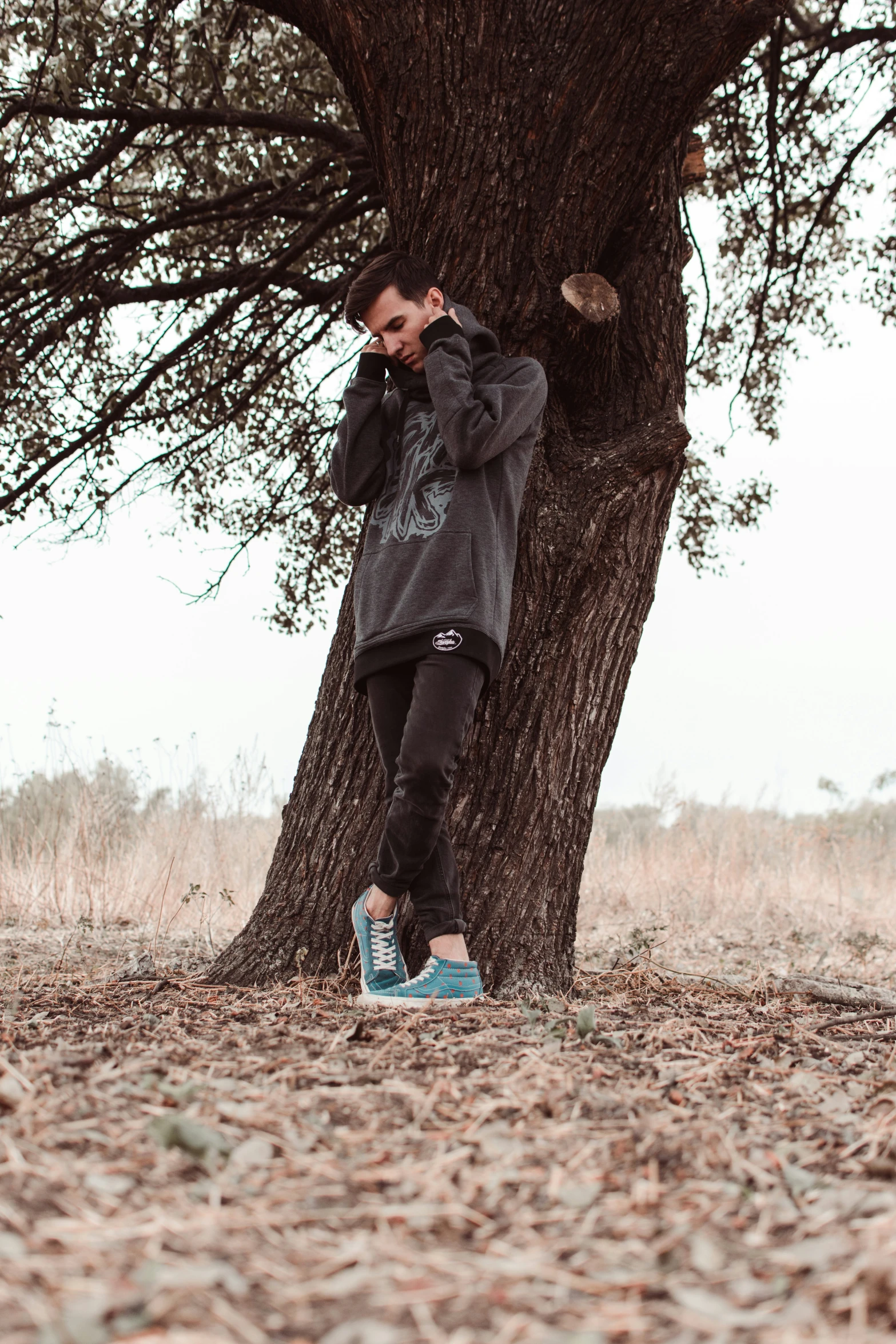 a man standing next to a tree while holding a phone