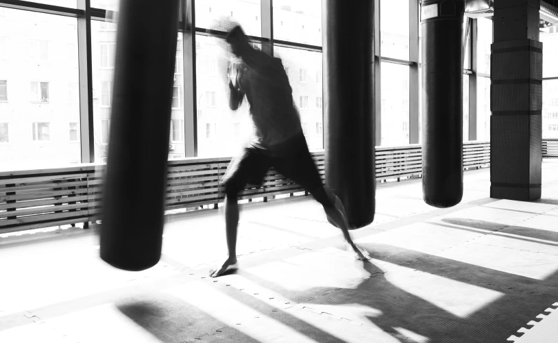 an artistic black and white po of a man doing a kick in a large building