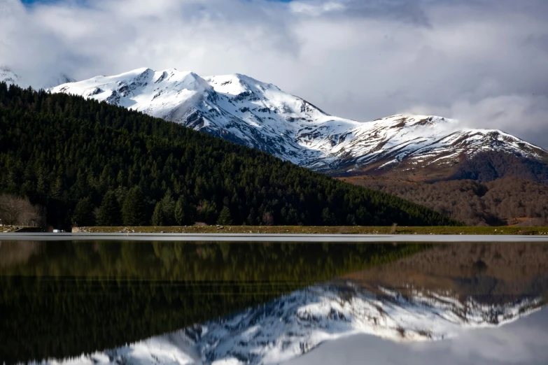 a snow covered mountain with trees and water