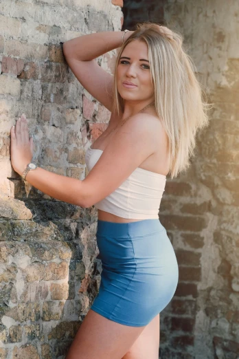 a beautiful blond with big  posing by a brick wall