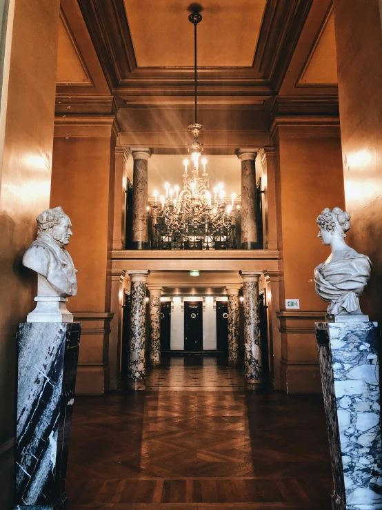 a large lobby with statues on the walls and chandelier hanging from the ceiling