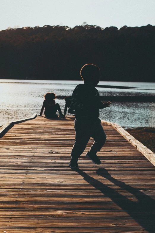 there is a  walking along a pier by the water