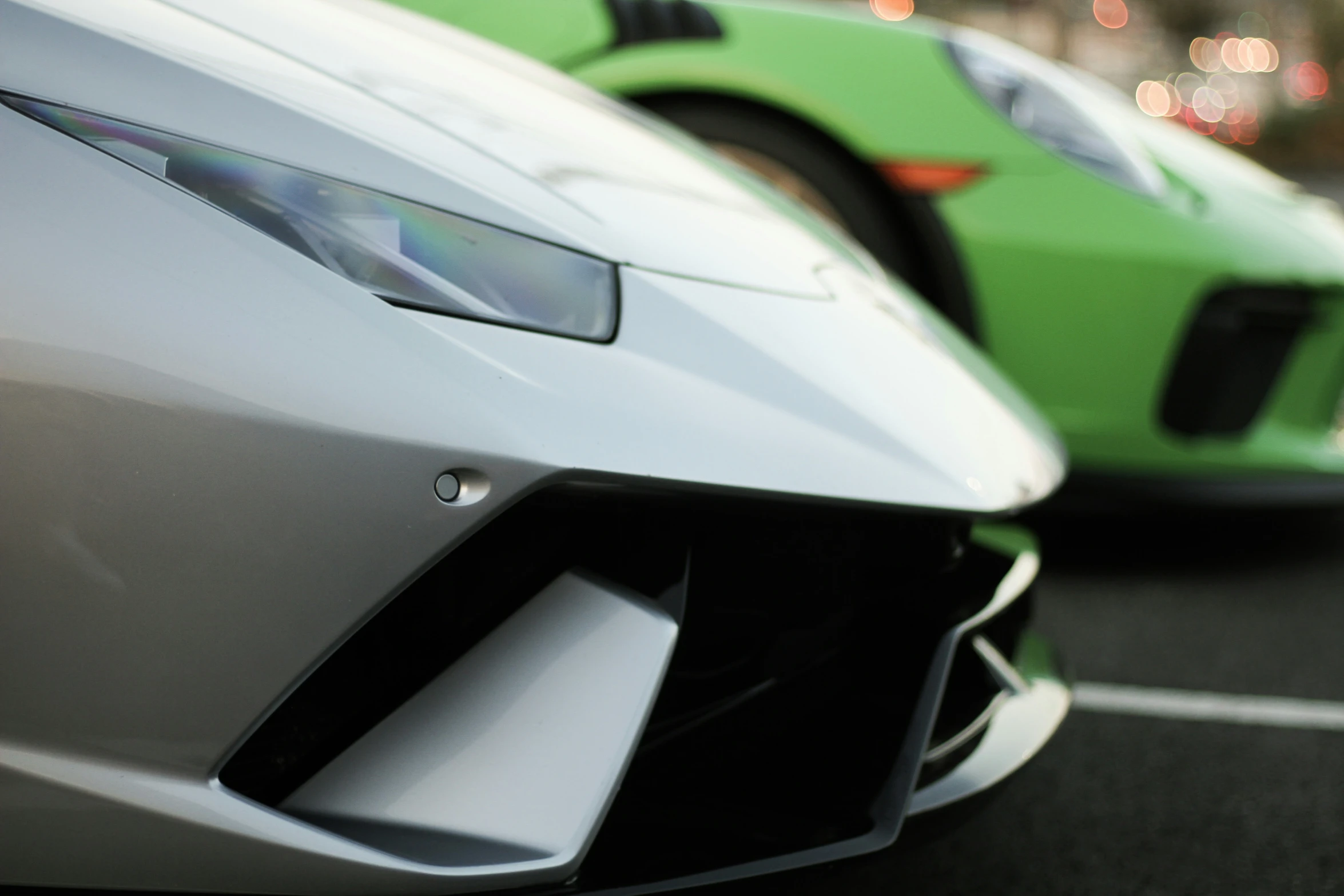 a couple of green sports cars are parked next to each other