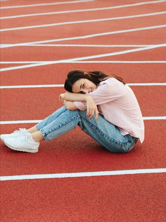 a  in white shirt and jeans sitting on red track