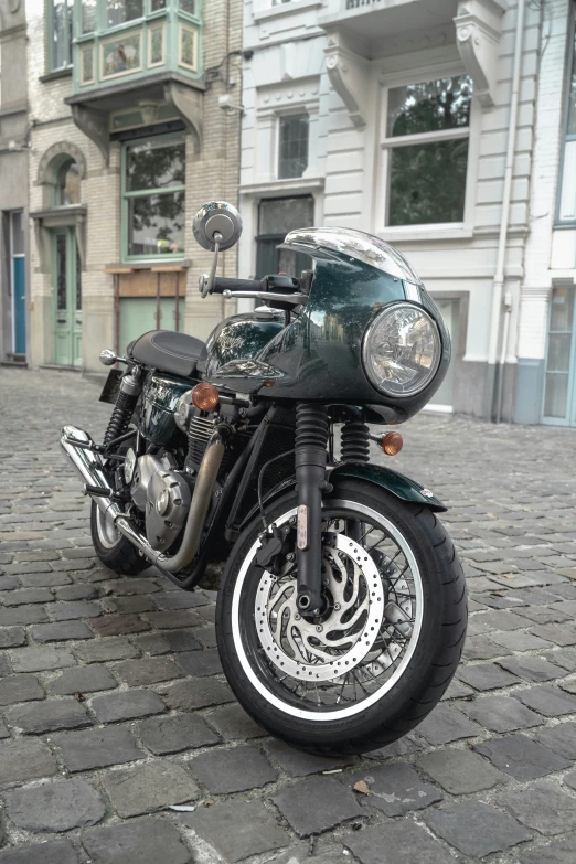 a black and green motorcycle parked on a brick street