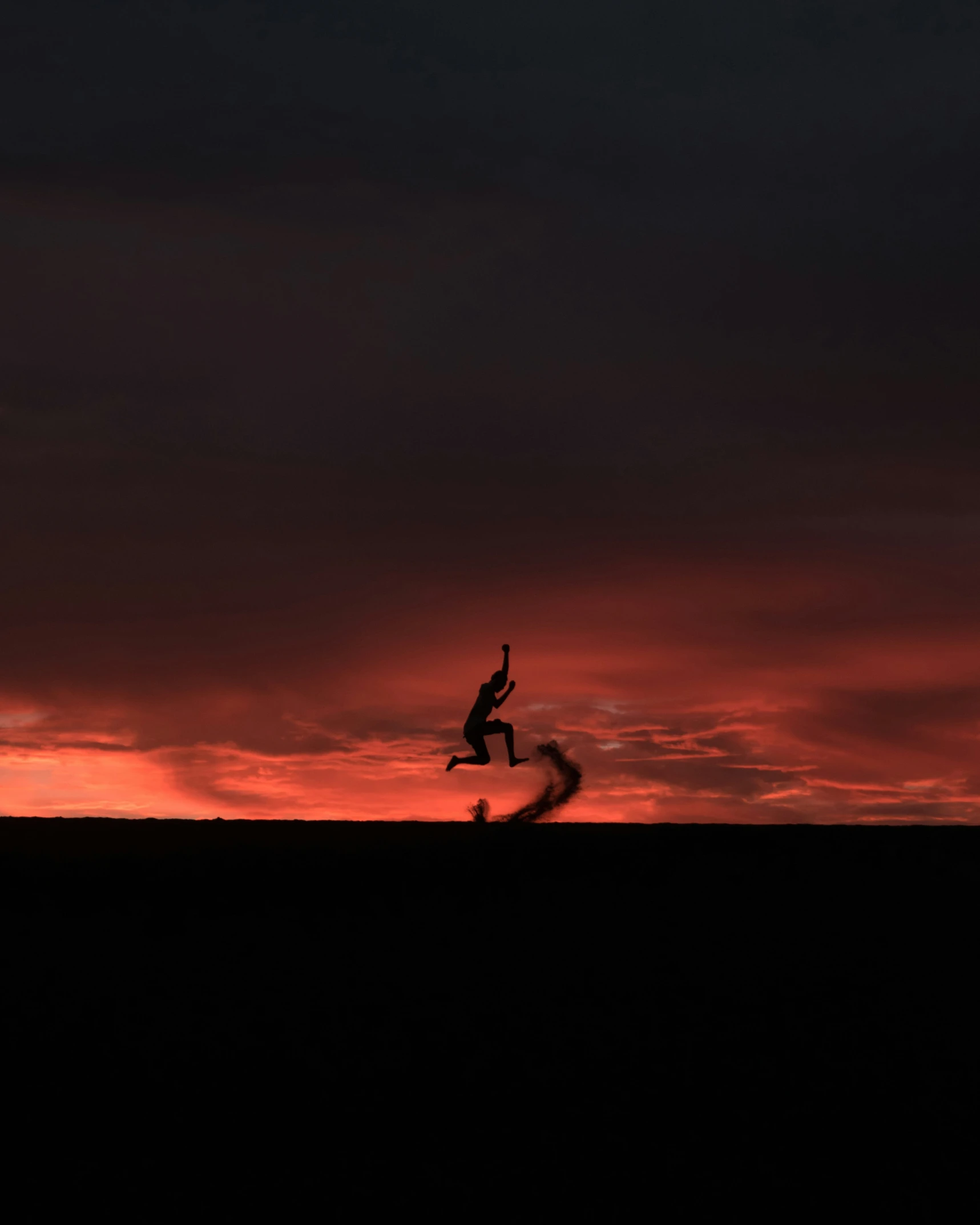 person jumping over a hill at sunset or sunrise