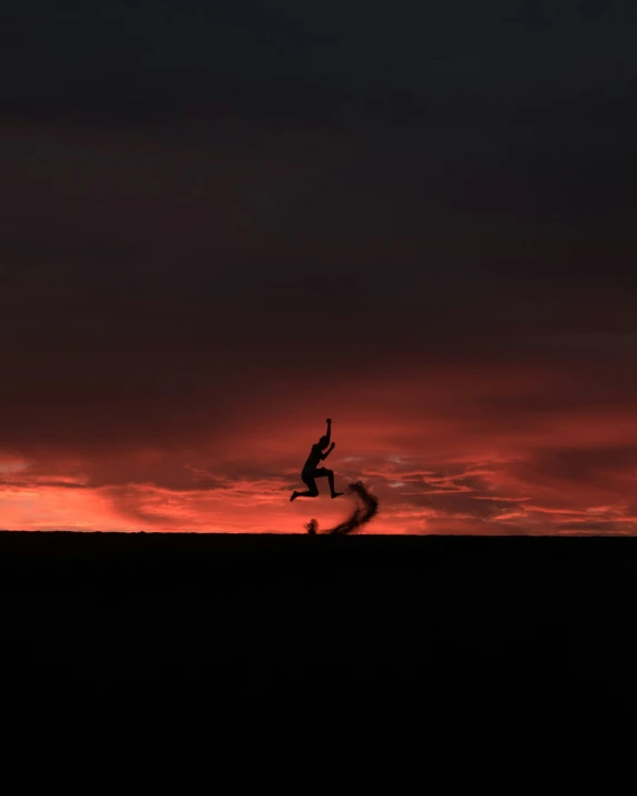 person jumping over a hill at sunset or sunrise