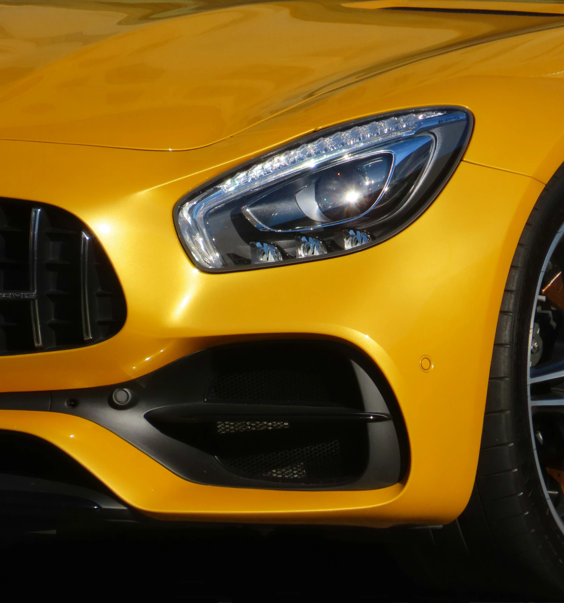 a close up of the headlight and grille on a yellow mercedes - benz sports car