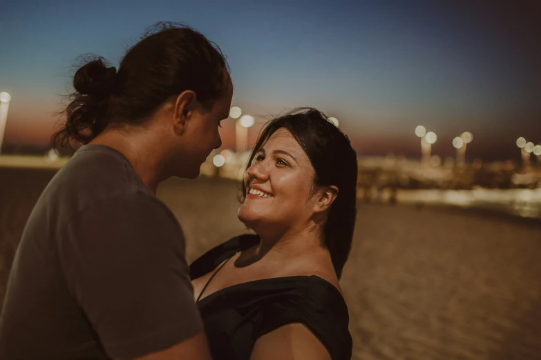 two people are standing close together by the water