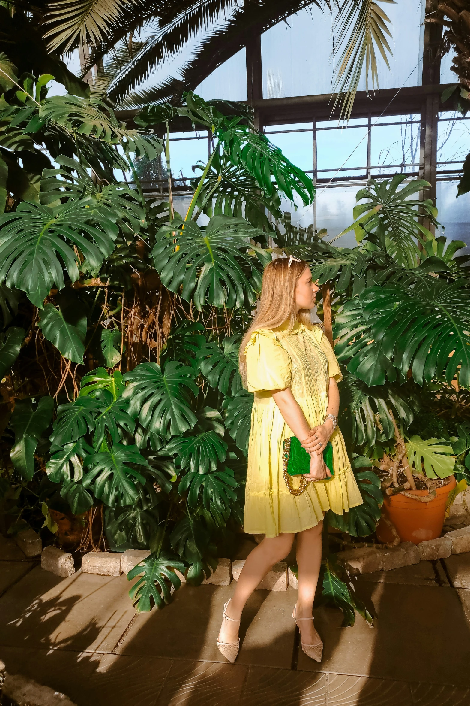 a woman stands in front of a lush green tree