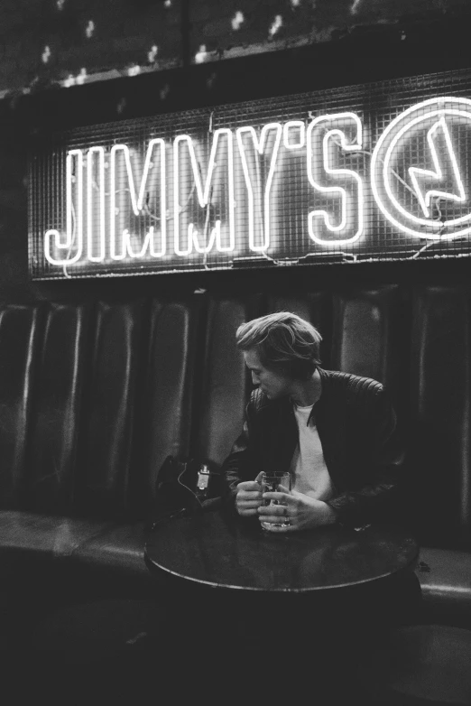 a neon sign with jimmys g is in front of a bar