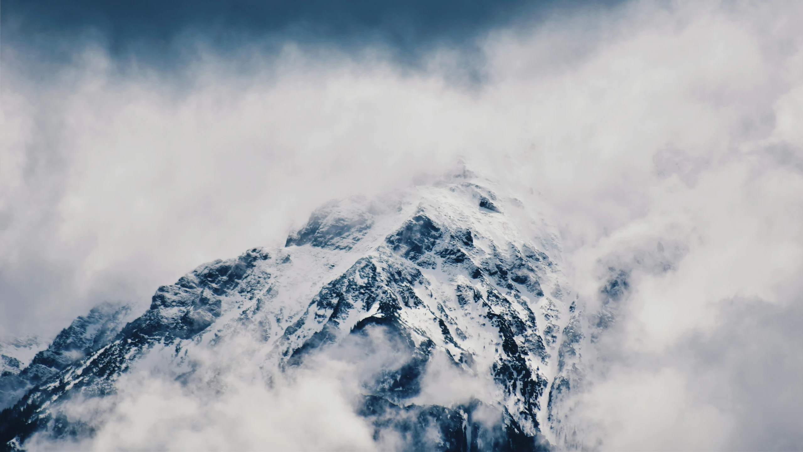 an uphill view of a mountain with clouds coming out from underneath