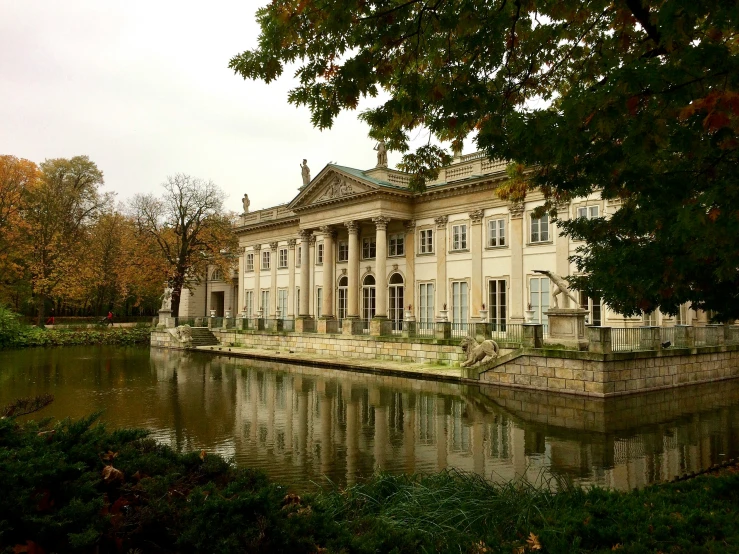 a large old mansion is overlooking the water and trees