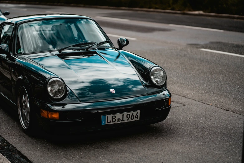 a green porsche 911 is parked on the side of the road