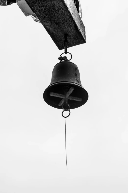 an old - fashioned bell hanging from a building with the sky in the background