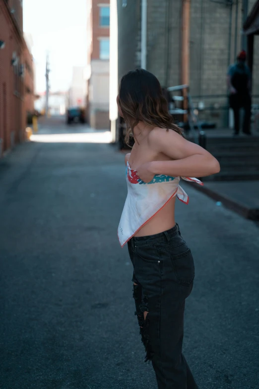 a woman in black jeans is posing by a wall