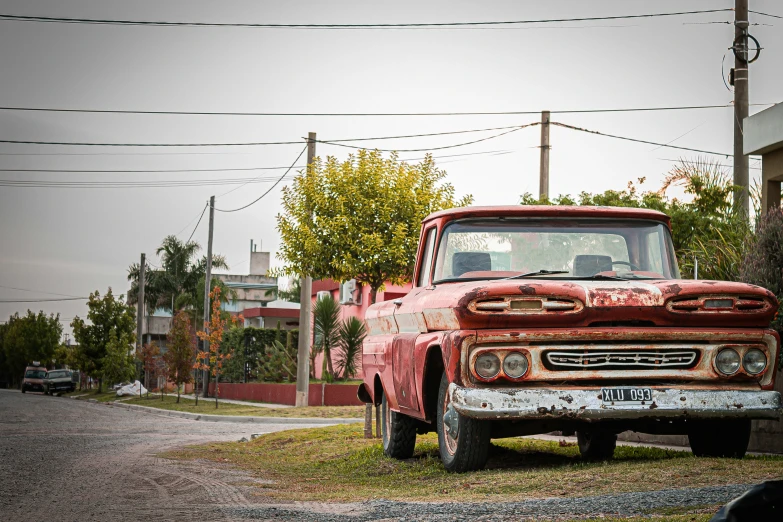 an old red truck parked on the side of a road