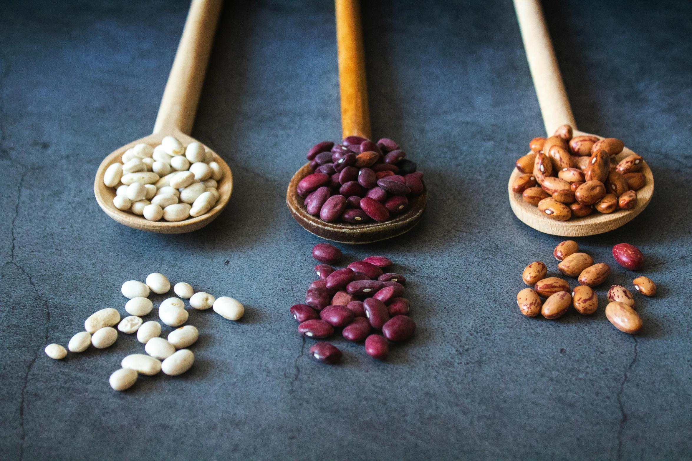 several wooden spoons filled with different kinds of nuts