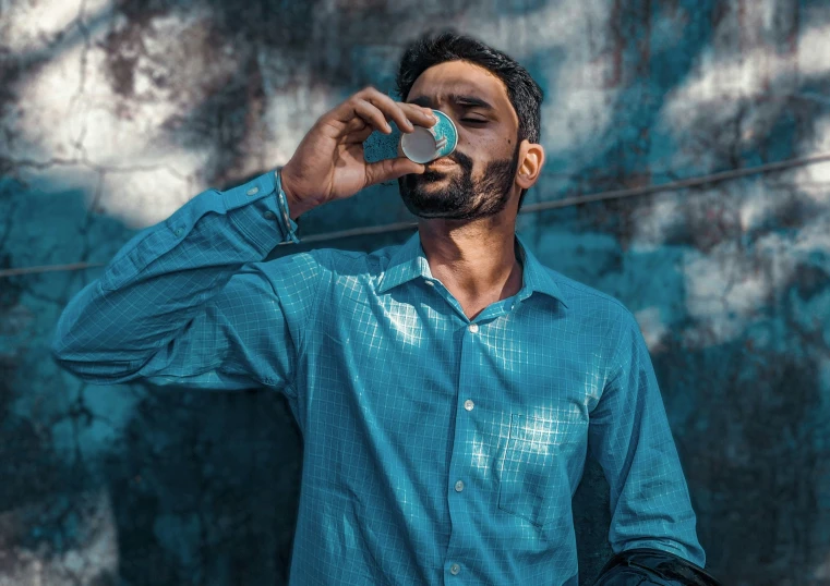 a man with a beard in a blue shirt is using his cell phone