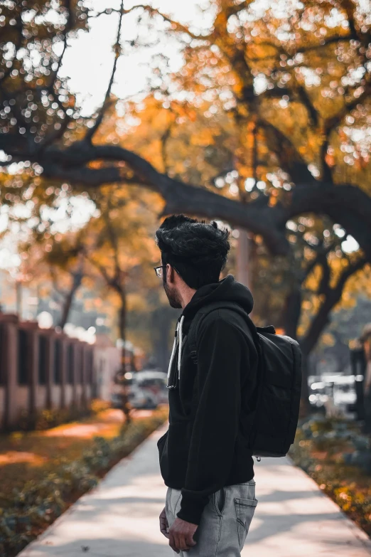 a young man walking down a sidewalk with a backpack