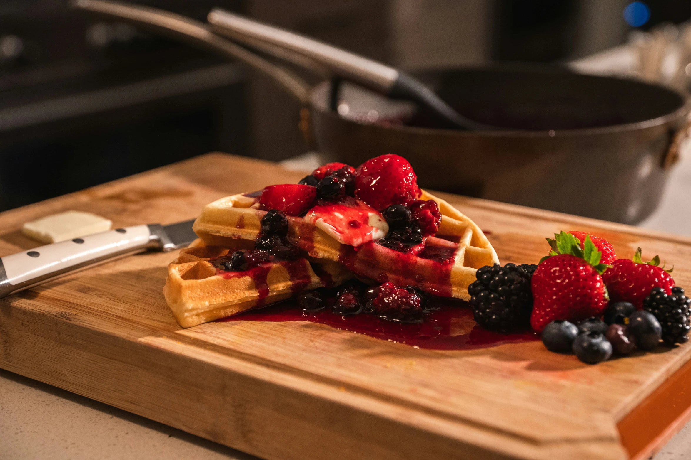 waffles, berries, and syrup on a  board