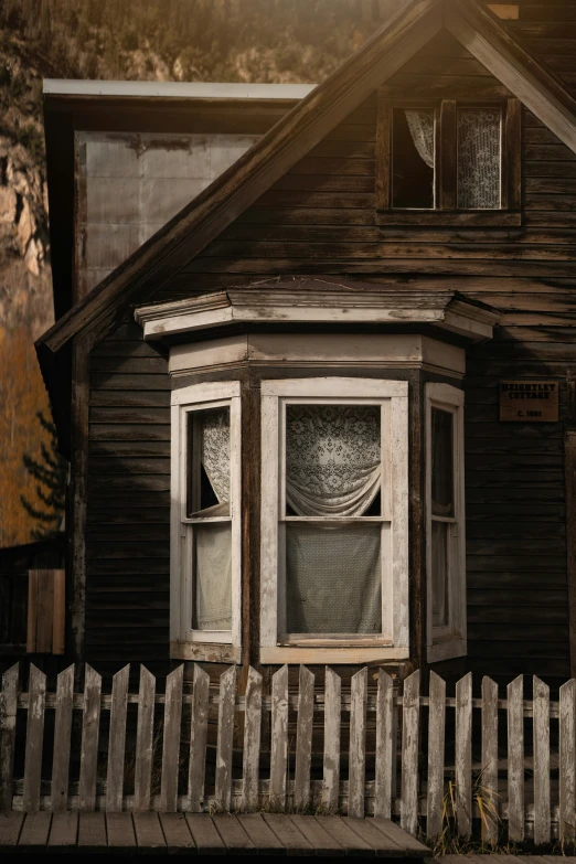 the window of an old house with a wood fence