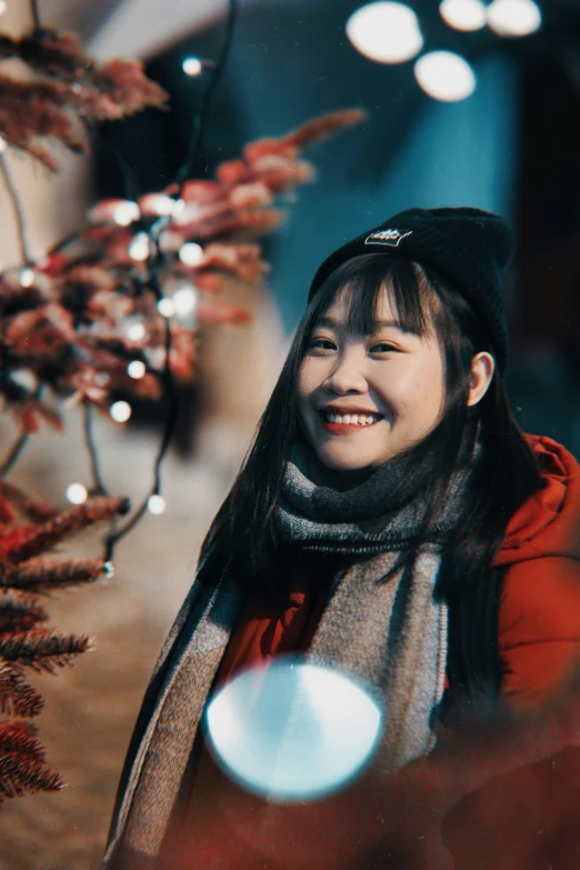 young woman standing in a park area smiling at soing